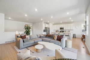 Living area with light wood finished floors and recessed lighting