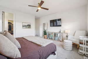 Carpeted bedroom featuring a spacious closet and a ceiling fan