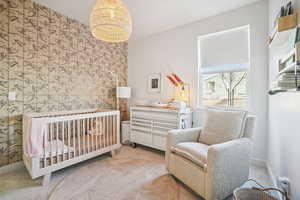 Bedroom featuring a crib, carpet flooring, an accent wall, and a baseboard heating unit
