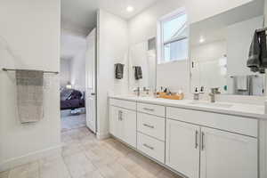 Ensuite bathroom with double vanity, a shower stall, and light tile patterned floors
