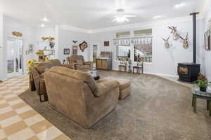 Living area with a pellet stove, light floors, and a ceiling fan