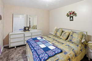 Bedroom featuring dark colored carpet and a textured ceiling