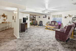 Carpeted living area featuring a ceiling fan and a textured ceiling