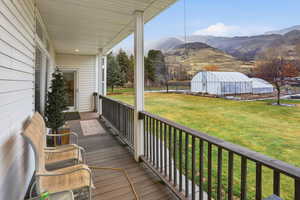 Deck with mountain view, greenhouse, and yard