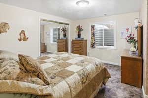Carpeted bedroom featuring a textured ceiling and a closet