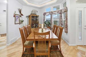 Dining space with a tray ceiling and light wood-style flooring