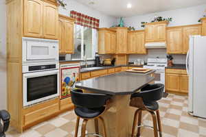 Kitchen with white appliances, a breakfast bar, and a kitchen island