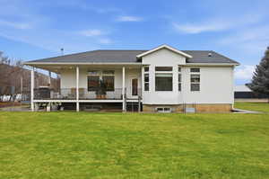 Rear view of house featuring covered porch, a shingled roof, and a yard