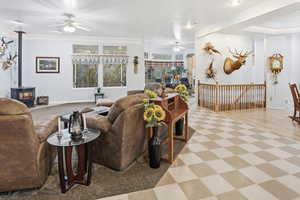 Living room with a pellet stove, plenty of natural light, ceiling fan, and light flooring