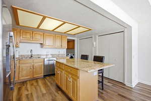Kitchen with a kitchen bar, stainless steel appliances, a kitchen island, light stone counters, and a textured ceiling