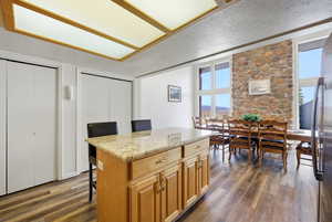 Kitchen featuring a kitchen breakfast bar, light stone counters, a center island, and dark wood finished floors