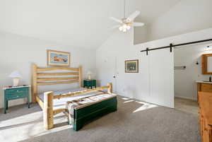Bedroom with a barn door, high vaulted ceiling, light carpet, and ceiling fan