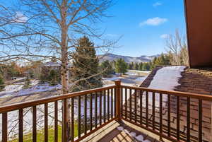 Snow covered deck with a balcony and a mountain view