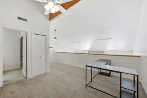 Unfurnished office featuring light carpet, a ceiling fan, high vaulted ceiling, and track lighting