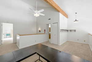 Hall with light carpet, an upstairs landing, beamed ceiling, and high vaulted ceiling