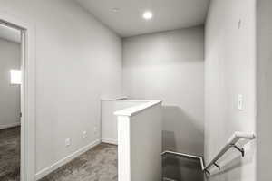 Corridor featuring an upstairs landing, light carpet, and recessed lighting