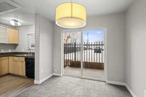 Unfurnished dining area with light colored carpet, healthy amount of natural light, and a textured ceiling
