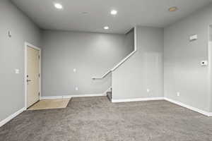 Empty room with recessed lighting, light carpet, and stairs