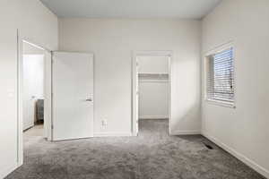 Unfurnished bedroom featuring a walk in closet and carpet