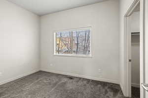 Unfurnished bedroom featuring dark carpet and baseboards