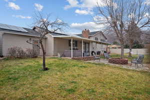 Back of property with an outdoor fire pit, a patio, a hot tub, a fenced backyard, and solar panels