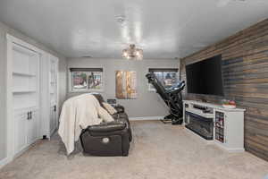 Living room with a textured ceiling, light carpet, plenty of natural light, built in features, and an accent wall