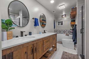 Bathroom featuring double vanity, light tile patterned floors, a stall shower, and a soaking tub