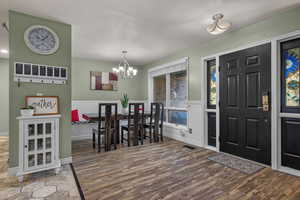 Foyer with wood finished floors, wainscoting, and a chandelier