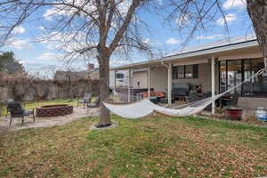 Rear view of property with a patio, an outdoor fire pit, and a yard