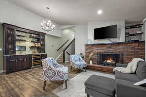 Living area with stairs, wet bar, dark wood-style flooring, wine cooler, and a brick fireplace