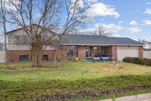 View of front of house with brick siding, a patio area, and a front lawn