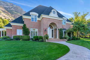 French provincial home with a front yard, roof with shingles, and brick siding