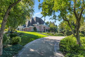 View of front facade with brick siding, a shingled roof, and a front lawn