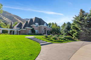 French provincial home featuring a front lawn and brick siding