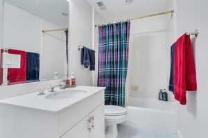 Bathroom with vanity, shower / bath combo, light tile patterned floors, and a textured ceiling
