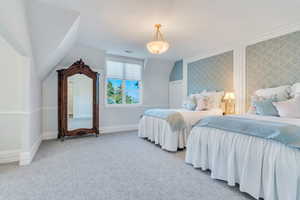Carpeted bedroom featuring vaulted ceiling, an accent wall, and wallpapered walls