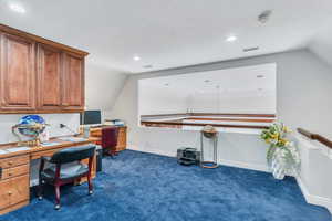 Home office featuring dark carpet, vaulted ceiling, recessed lighting, and a textured ceiling