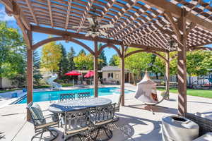 View of patio with ceiling fan, a pergola, outdoor dining area, and a playground