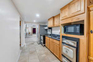 Kitchen featuring arched walkways, black microwave, dark stone countertops, gas range oven, and freestanding refrigerator