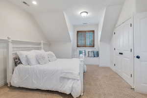 Bedroom featuring light colored carpet, a closet, and lofted ceiling