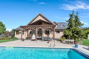 Rear view of house featuring a patio area, stucco siding, a pergola, and an outdoor pool
