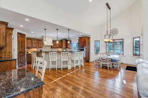 Kitchen featuring a kitchen bar, brown cabinets, high vaulted ceiling, a large island, and light wood floors