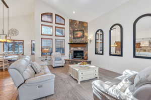 Living area featuring high vaulted ceiling, a stone fireplace, a chandelier, and recessed lighting