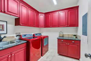 Laundry room with cabinet space, electric panel, washing machine and clothes dryer, and light tile patterned floors