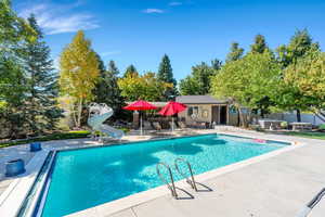 View of pool featuring a water slide, a patio, a jacuzzi, and a pool house