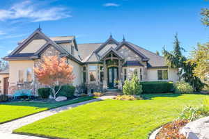 French country style home with stone and stucco siding, and a beautifully landscaped front yard