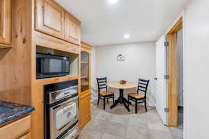 Kitchen featuring black appliances, light brown cabinetry, light tile patterned floors, recessed lighting, and dark countertops