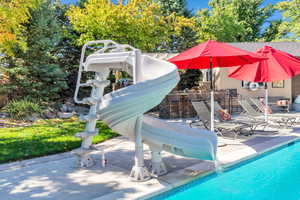 Outdoor pool with a water slide and a patio area
