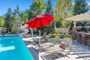View of pool featuring a water slide, a patio, a fenced backyard, and a pergola
