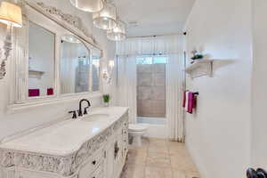 Full bath featuring vanity, shower / bath combo with shower curtain, and light tile patterned floors